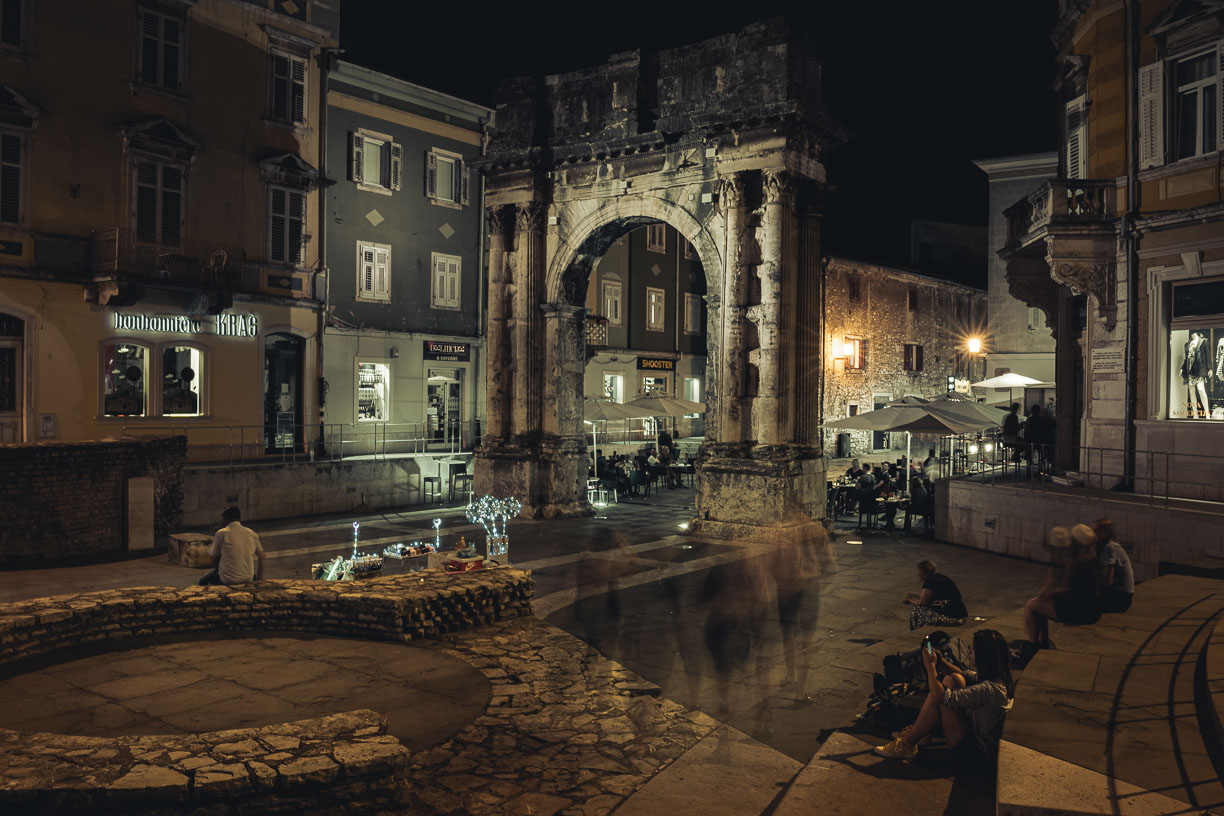 long exposure people like ghost in front of Roman gate in Pula